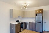 Located at 240 Mack Ave in Detroit, MI, this thoughtfully designed one-bedroom, one-bathroom unit makes efficient use of its compact footprint. The open-plan living, dining, and kitchen area serves as the heart of the home, featuring light wood-look flooring that flows seamlessly throughout. The kitchen is outfitted with modern two-tone cabinetry — pairing warm wood lower cabinets with light upper cabinets — complemented by white quartz countertops and a full suite of stainless steel appliances, including a gas range, dishwasher, and refrigerator. A stylish sputnik chandelier adds a contemporary touch overhead. The living area is anchored by a bold navy accent wall with two large windows that invite natural light and views of the surrounding neighborhood. The bedroom is a comfortable, well-proportioned room with clean white walls, light flooring, and a built-in closet. A slim window provides additional natural light. The bathroom features a walk-in shower with white tile surround, matte black fixtures, and wood-look flooring for a clean, modern aesthetic. A dedicated laundry area and a closet round out the unit's practical amenities, making this an efficiently designed and stylishly finished space.
