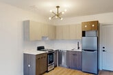 Located at 240 Mack Ave in Detroit, MI, this thoughtfully designed one-bedroom, one-bathroom unit makes efficient use of its compact footprint. The open-plan living, dining, and kitchen area serves as the heart of the home, featuring light wood-look flooring that flows seamlessly throughout. The kitchen is outfitted with modern two-tone cabinetry — pairing warm wood lower cabinets with light upper cabinets — complemented by white quartz countertops and a full suite of stainless steel appliances, including a gas range, dishwasher, and refrigerator. A stylish sputnik chandelier adds a contemporary touch overhead. The living area is anchored by a bold navy accent wall with two large windows that invite natural light and views of the surrounding neighborhood. The bedroom is a comfortable, well-proportioned room with clean white walls, light flooring, and a built-in closet. A slim window provides additional natural light. The bathroom features a walk-in shower with white tile surround, matte black fixtures, and wood-look flooring for a clean, modern aesthetic. A dedicated laundry area and a closet round out the unit's practical amenities, making this an efficiently designed and stylishly finished space.