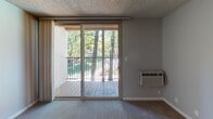 Located at 1812 Trinity Ave in Walnut Creek, CA, this ground-floor apartment offers a well-designed single-level layout with a blend of comfort and functionality. The living area is finished with rich wood-style flooring, crown molding, and a ceiling fan, creating a welcoming atmosphere. Sliding glass doors flood the space with natural light and open to a view of the landscaped surroundings, bringing a sense of openness to the interior.

The kitchen is outfitted with warm honey-toned cabinetry, dark granite-style countertops, stainless steel appliances including a refrigerator, microwave, and range, and a tall pantry cabinet for ample storage. Crown molding carries throughout, adding a polished, cohesive detail to the space.

The bedroom features soft carpeting, neutral gray walls, and a large window that frames a picturesque view of mature trees outside, providing both natural light and a serene outdoor connection.

The bathroom is finished with wood-style flooring, a warm wood vanity with dark countertops, a large mirror with a multi-bulb vanity light fixture, and a full tub-shower combination. The overall design of the unit is clean, neutral, and move-in ready, suited for comfortable everyday living in the heart of Walnut Creek.