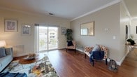 Located at 57 Charles St in Mansfield, Massachusetts, this single-floor residence offers a thoughtfully designed layout with cohesive finishes throughout. The living area is anchored by rich hardwood flooring and elegant crown molding, with a sliding glass door that opens to a private balcony, flooding the space with natural light and providing views of the surrounding neighborhood. A wall mirror and neutral-toned walls contribute to an open, airy atmosphere.

The kitchen is efficiently designed with white raised-panel cabinetry, granite countertops, and a full suite of stainless steel appliances, including a refrigerator, range, over-the-range microwave, and dishwasher. A granite-topped peninsula extends into the dining area, offering casual seating and additional prep space, all set over hardwood flooring with crown molding above.

The two bedrooms are carpeted and generously sized, each receiving natural light through large windows with views to the exterior. Both bathrooms mirror the kitchen's finishes, featuring granite-topped white vanities, wood-framed mirrors, tile flooring, and shower/tub combinations. The overall design maintains a consistent, refined palette throughout the residence.