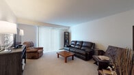 This single-floor residence on White Oak Circle in Menomonee Falls, Wisconsin, offers a well-organized layout with clearly defined living spaces. The living room is generously proportioned, featuring neutral-toned carpet, smooth white walls, and a large sliding glass door dressed with vertical blinds that allow ample natural light to filter in. The open feel of the room is enhanced by the understated color palette and clean sightlines throughout.

The kitchen is appointed with warm oak cabinetry offering abundant storage, light-toned laminate countertops, a double-basin stainless steel sink, and wood-look flooring that adds a practical, easy-to-maintain surface underfoot. White appliances, including a full-size refrigerator and electric range, complete the functional setup.

The bedroom is a calm, comfortable retreat with soft carpet, neutral walls, and a window fitted with horizontal blinds that provide natural light while maintaining privacy. Vaulted ceiling details lend a sense of openness to the room. The space comfortably accommodates a queen-sized bed and additional furniture. Overall, the home presents a straightforward, functional design with a quiet residential setting in a well-established Menomonee Falls neighborhood.