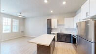 Located at Winghaven Pointe in O'Fallon, Missouri, this single-floor, one-bedroom, one-bathroom unit offers a thoughtfully designed open-concept layout. The kitchen and living area flow seamlessly together, anchored by a standout kitchen featuring a two-tone cabinet design — rich dark-stained lower cabinetry paired with crisp white upper cabinets. A center island with a light quartz countertop provides additional prep and seating space, while stainless steel appliances, including a refrigerator, range, microwave, and dishwasher, complete the well-equipped kitchen. Light wood-style flooring runs throughout the entire unit, creating a clean and cohesive look. The living area benefits from a ceiling fan, recessed lighting, and a glass door flanked by windows that invite natural light and provide outdoor views. The bedroom is a comfortable, well-proportioned room with high ceilings and continues the light flooring aesthetic. A dedicated closet offers practical storage. The bathroom includes a soaking tub with overhead rod, a toilet, and light wood-style flooring consistent with the rest of the unit. Clean neutral wall tones and modern finishes give the space a fresh, move-in-ready feel throughout.