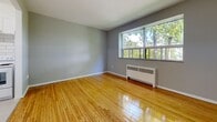 Located on Main St W in Hamilton's vibrant west end, this 2-bedroom, 1-bathroom unit offers a practical and well-maintained layout across a single floor. Warm-toned hardwood flooring flows throughout the living, dining, and bedroom areas, lending the space a cohesive and inviting character. The open living room is bright and airy, benefiting from large windows that frame lush green tree views and fill the room with natural light. A radiator heating unit ensures comfortable warmth throughout the seasons. The kitchen is clean and functional, featuring white shaker-style cabinetry, a classic white subway tile backsplash extending to the ceiling, light stone countertops, a stainless steel sink, and a white range — all set on light tile flooring. Both bedrooms carry the same warm hardwood flooring, neutral grey walls, and large windows with tranquil outdoor views. Each bedroom is equipped with a built-in bi-fold closet for ample storage. The bathroom features a full soaking tub with a tiled surround in a crisp white finish. The overall aesthetic is clean, neutral, and functional, making this a comfortable and practical residence in a well-connected Hamilton neighbourhood.
