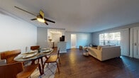 Located at 640 W Lincoln Ave in Escondido, CA, this single-floor residence offers a well-designed, functional layout with modern finishes throughout. The open-concept living and dining area serves as the heart of the home, featuring rich hardwood-style flooring, neutral gray walls, and a ceiling fan overhead. The living area flows seamlessly into the dining space, which comfortably accommodates a round table and chairs beneath a lighted ceiling fan. Natural light filters in through sliding glass doors that lead to an outdoor area with views of surrounding greenery. The galley-style kitchen is outfitted with white shaker cabinetry, light stone countertops, a stainless steel sink, and a full suite of stainless steel appliances including a refrigerator, range, microwave, and dishwasher. The bedrooms are carpeted for comfort; one features dual windows with outdoor tree views, while another includes mirrored sliding closet doors and direct access to a bathroom. The bathroom is clean and bright, with a white vanity topped with a marble-style countertop, a wood-framed mirror, and a shower/tub combination with a window for natural light. The space combines practical design with contemporary touches, making it a comfortable and inviting residence.