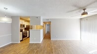 This single-floor residence offers a thoughtfully designed open-concept layout that seamlessly connects the kitchen and living areas. The kitchen is well-equipped with stainless steel appliances, ample white cabinetry, a double sink, and a convenient peninsula that defines the space while maintaining an open feel. Adjacent to the kitchen is an in-unit laundry area for added convenience. The spacious living room is a standout feature, boasting a classic fireplace with a white surround, a ceiling fan with light fixture, and sliding glass doors fitted with vertical blinds that allow natural light to pour in. Wood-look plank flooring runs consistently throughout the home, complemented by neutral gray walls and textured ceilings that add character. A central hallway connects the living area to the private rooms, each featuring ceiling fans, large windows with blinds, and generous natural light. The bathroom is clean and functional, offering a tub-shower combination, a vanity with sink, and matching neutral finishes. Overall, the space presents a bright, cohesive, and practical living environment with a comfortable, move-in-ready ambiance.