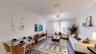 This thoughtfully designed single-floor residence offers a seamless open-concept layout that connects the living, dining, and kitchen areas into one cohesive and functional space. The living area features crown molding, a ceiling fan, and wood-look flooring, with natural light streaming through large windows dressed in sheer white curtains. The dining area flows naturally into the living space, creating an ideal environment for both everyday living and entertaining.

The kitchen is a standout feature, showcasing rich dark wood cabinetry, granite countertops, stainless steel appliances, track lighting, and a peninsula with bar seating — combining style and practicality in equal measure.

The primary bedroom is generously sized, offering plush carpeting and direct access to a walk-in closet. A secondary bedroom provides comfortable accommodations with soft carpeting and warm ambient lighting. The bathroom is finished with a granite-topped dark wood vanity, wood-look tile flooring, and a tiled tub-shower combination with marble-style surrounds.

A dedicated laundry room with wire shelving and a full-size washer and dryer adds everyday convenience. The entry foyer provides a welcoming transition into the home. Throughout, the neutral color palette and consistent finishes create a cohesive, modern aesthetic.