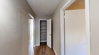 This single-floor home offers a clean, functional layout with consistent neutral tones and wood-style flooring throughout. The living areas are bright and open, benefiting from natural light that filters through blinds-covered windows, creating a warm and welcoming ambiance. Ceiling fans are present in the bedrooms, providing both comfort and airflow, while the warm-toned walls and white baseboards lend a cohesive, tidy aesthetic across the space. The kitchen is equipped with rich wood cabinetry, light granite-style countertops, a black dishwasher, and a stainless steel refrigerator, offering a practical and well-appointed cooking space. The hallway serves as a central connector and features a built-in shelved closet with a white panel door, providing ample storage for linens or pantry items. An additional door off the hallway leads to further rooms, showcasing the thoughtful flow of the floor plan. The bathroom includes a full tub-shower combination, a wall-mounted medicine cabinet with mirror, a wood-toned vanity with white countertop, and tile flooring, presenting a clean and classic design. Overall, the home delivers a straightforward, move-in-ready environment with practical features and a neutral palette suited to a variety of lifestyles.