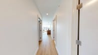 This well-appointed two-bedroom, two-bathroom unit in Calgary, AB offers a modern and cohesive design throughout. Light hardwood flooring runs through the main living areas and bedrooms, complemented by crisp white walls that create a bright, airy atmosphere. A clean entry hallway connects the key spaces with ease.

The kitchen is a standout feature, showcasing warm walnut cabinetry extending to the ceiling, white quartz countertops, a subway tile backsplash, and a full suite of stainless steel appliances. A central island provides additional counter space and integrates seamlessly with the adjacent dining area.

The primary bedroom is generously sized, featuring large windows that frame sweeping city views, flooding the room with natural light. The second bedroom offers a quieter feel, with a sliding closet and a high horizontal window for added brightness. Both rooms continue the light hardwood flooring found throughout the unit.

The two bathrooms are finished with large-format tile flooring, walnut vanity cabinetry, white quartz countertops, and wide mirrors, maintaining a consistent and refined aesthetic. Recessed lighting throughout the unit ensures consistent illumination. Overall, the space delivers a clean, contemporary feel well-suited to modern urban living in Calgary.