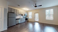 This well-designed single-floor unit in Atlanta, GA (30318) offers a thoughtfully laid-out open-concept living space that seamlessly connects the kitchen and main living area. Rich, dark hardwood-style flooring runs throughout, lending warmth and cohesion to the entire space. The kitchen is a standout feature, boasting gray shaker-style cabinetry, granite countertops, a classic white subway tile backsplash, and a full suite of stainless steel appliances including a refrigerator, dishwasher, electric range, and over-the-range microwave. Natural light filters in through multiple windows fitted with blinds, brightening the open living area, which is further complemented by a modern ceiling fan. A private exterior door provides convenient access from the living space. Practicality is a priority, with an in-unit stacked washer and dryer tucked neatly into a dedicated closet alongside an additional storage closet. The bathroom is elegantly finished with white hexagonal tile flooring, a subway-tiled soaking tub and shower surround, a granite-topped vanity with gray cabinetry, and brushed gold hardware accents. The overall ambiance is clean, contemporary, and move-in ready.