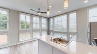 Located at 651 Meeting St in Charleston, SC, this single-floor residence offers a thoughtfully designed open-concept layout with clean, contemporary finishes throughout. Light wood-tone flooring runs consistently across the entire space, creating a cohesive and airy feel.

The kitchen serves as the heart of the home, anchored by a central island with a white quartz countertop and built-in sink. Stainless steel appliances — including a full-size refrigerator, electric range, and over-the-range microwave — are complemented by crisp white upper cabinetry and two-toned gray lower cabinets. Pendant lighting and recessed ceiling lights provide both task and ambient illumination. An abundance of large windows with horizontal blinds floods the kitchen and living area with natural light while offering views of the surrounding neighborhood.

The bedroom is a calm, neutral space featuring light gray walls, a ceiling fan, and a pair of reach-in closets with white panel doors, offering generous storage. The full bathroom is well-appointed with a tub/shower combination featuring white subway tile surround, a vanity with quartz countertop and gray cabinetry, and wood-look flooring that ties into the rest of the unit. Recessed lighting and a large mirror complete the space efficiently.