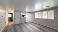 Located at 51 Williamtowne Ct in Buffalo, NY, this one-bedroom, one-bathroom unit offers a practical and well-organized single-floor layout. The combined living and dining area is a welcoming, open space featuring plush carpeting, neutral gray walls, and multiple windows that invite generous natural light and views of the surrounding greenery. A pass-through opening connects this living space to the kitchen, maintaining an airy, connected feel throughout.

The galley-style kitchen is thoughtfully designed with gray shaker cabinets, light stone-look countertops, a stainless steel sink with a matte black faucet, and light wood-look vinyl plank flooring. Black appliances — including a refrigerator, electric range, microwave, and dishwasher — provide a modern contrast to the bright cabinetry. A window above the appliances brings in additional natural light.

The bedroom is a comfortable, carpeted retreat with two windows overlooking the outdoors, soft neutral tones, and two closet doors, offering ample storage. The full bathroom is clean and functional, featuring a white vanity with a large mirror, a tub/shower combo with tile surround, and wood-look vinyl flooring that ties the space together with a consistent, contemporary aesthetic throughout the unit.