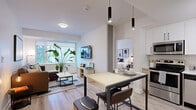 Located at 770 Brookfield Rd in Ottawa, this thoughtfully designed 2-bedroom, 2-bathroom unit offers a smart and efficient layout across a single floor. Light wood-toned flooring flows throughout, lending a clean, cohesive aesthetic to the entire space.

The open-concept living and dining area is bright and welcoming, featuring a large window that brings in natural light and frames views of the surrounding neighbourhood. The dining area includes a modern bar-height table with pendant lighting overhead, seamlessly connecting to the living room, which offers a comfortable seating arrangement and wall-mounted television.

The kitchen is well-appointed with two-tone cabinetry — white uppers paired with warm wood lowers — complemented by a herringbone-patterned tile backsplash, stainless steel appliances including a full-size refrigerator and range, and a clean white countertop with an undermount sink.

Both bedrooms are comfortably scaled, each featuring a window with outdoor views, light wood storage units, and a calm, neutral palette. The primary bedroom provides ample space for a full bedroom suite.

The two bathrooms mirror each other in design, each featuring vertical subway-tiled walk-in showers, wood-finish vanities with white countertops, and light flooring — maintaining the unit's consistent modern aesthetic throughout.