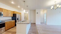 This well-appointed 2-bedroom, 2-bathroom residence in Johnstown, Colorado offers a thoughtfully designed single-floor layout that balances comfort and functionality. The open-concept kitchen serves as the heart of the home, showcasing warm natural wood cabinetry, granite countertops, stainless steel appliances, and a central island with an integrated sink and stylish pendant lighting overhead. Light hardwood-style flooring flows throughout the main living areas, creating a seamless transition between spaces.

The living and dining areas are generously sized, featuring plush carpeting, a ceiling fan, and an elegant chandelier. Large windows allow ample natural light to fill the room, enhancing the bright, airy atmosphere throughout.

The primary bedroom is a comfortable retreat with soft carpeting, a ceiling fan, and a window overlooking the exterior. Its en-suite bathroom features a dual-sink vanity with granite countertops, warm wood cabinetry, and direct access to a spacious walk-in closet with built-in shelving. The second bedroom mirrors the same carpet and ceiling fan details, with its own nearby full bathroom that includes a single vanity and hardwood-style flooring. Additional highlights include two closets, a dedicated laundry area, and consistent neutral finishes throughout.