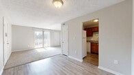 This 2-bedroom, 1-bathroom residence is laid out entirely on a single floor, offering a straightforward and functional floor plan. The living room serves as the central gathering space, featuring a combination of wood-look hard-surface flooring and plush carpet, neutral gray walls, a textured ceiling, and a sliding glass door that lets in generous natural light and provides access to an outdoor area. Adjacent to the living room, the kitchen is well-appointed with warm medium-toned wood cabinetry, granite-look countertops, and white appliances including a refrigerator, electric range, and dishwasher, all set atop durable wood-look flooring. Both bedrooms are carpeted and finished in soft, neutral tones. The primary bedroom offers a comfortable footprint, while the second bedroom features a sliding-door closet and a window overlooking the exterior. The shared bathroom includes a wood-vanity with a light stone-look countertop and white subway tile surround. A dedicated closet provides additional storage. Throughout the residence, clean white trim, consistent neutral paint tones, and ample natural light from multiple windows contribute to a bright, understated, and move-in-ready ambiance.