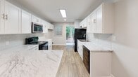 Located at 910 Shellbrook Ct in Raleigh, NC, this single-floor home offers a thoughtfully updated interior with a clean, modern aesthetic throughout. The open living area welcomes you with warm hardwood-style flooring, neutral-toned walls, and a large window that fills the space with natural light, creating a bright and inviting atmosphere.

The kitchen stands out as a centerpiece of the home, showcasing striking marble-look quartz countertops, crisp white shaker cabinetry with brushed nickel hardware, and a light gray subway tile backsplash. A kitchen island provides additional prep and storage space, while wood-look flooring ties the room together. The kitchen is fully equipped with appliances including a range, microwave, refrigerator, and dishwasher, and features direct access to an outdoor area.

The bedrooms are finished with plush carpeting and neutral walls, offering a comfortable retreat. Each room benefits from natural light provided by windows with blinds, and ceiling fans ensure year-round comfort. One bedroom includes a walk-in closet for added convenience. The bathroom features a clean, all-white design with a tub-shower combination, white vanity, and wood-look tile flooring, rounding out this well-appointed single-level home.