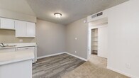 Located at 15082 N 59th Ave in Glendale, Arizona, this one-bedroom, one-bathroom residence offers a well-organized single-floor layout designed for efficient, comfortable living. The living room is a welcoming space featuring plush carpeting, a ceiling fan with light fixture, textured ceilings, and a sliding glass door that opens onto a private covered balcony overlooking lush greenery — bringing in natural light and outdoor views. The galley-style kitchen is efficiently designed with ample white cabinetry, white countertops, wood-look flooring, and a full suite of white appliances including a range, dishwasher, and refrigerator. The bedroom is a comfortable retreat, also finished with soft carpeting, a window with vertical blinds for natural light, and two closets offering generous storage. The bathroom is clean and functional, featuring wood-look flooring, a vanity, toilet, and a full tub/shower combination. Throughout the residence, neutral tones, white trim, and consistent finishes create a cohesive and tidy aesthetic. The transition between the wood-look flooring in the kitchen and dining area and the carpet in the living and sleeping areas adds practical definition to each zone.