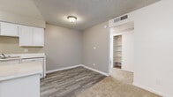 Located at 15082 N 59th Ave in Glendale, Arizona, this one-bedroom, one-bathroom residence offers a well-organized single-floor layout designed for efficient, comfortable living. The living room is a welcoming space featuring plush carpeting, a ceiling fan with light fixture, textured ceilings, and a sliding glass door that opens onto a private covered balcony overlooking lush greenery — bringing in natural light and outdoor views. The galley-style kitchen is efficiently designed with ample white cabinetry, white countertops, wood-look flooring, and a full suite of white appliances including a range, dishwasher, and refrigerator. The bedroom is a comfortable retreat, also finished with soft carpeting, a window with vertical blinds for natural light, and two closets offering generous storage. The bathroom is clean and functional, featuring wood-look flooring, a vanity, toilet, and a full tub/shower combination. Throughout the residence, neutral tones, white trim, and consistent finishes create a cohesive and tidy aesthetic. The transition between the wood-look flooring in the kitchen and dining area and the carpet in the living and sleeping areas adds practical definition to each zone.