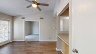 Located in Columbia, MD, this single-floor residence offers three bedrooms and one bathroom within a thoughtfully laid-out floor plan. The combined kitchen and living room serves as the heart of the home, highlighted by rich hardwood-style flooring, a ceiling fan, and vaulted ceiling elements that enhance the sense of openness. Large windows and a glass door flood the living area with natural light while offering pleasant views of the surrounding greenery.

The kitchen is well-appointed with light wood cabinetry, granite-style countertops, a peninsula with a stainless steel sink, track lighting, and black appliances including an electric range and dishwasher. A pass-through peninsula connects the kitchen seamlessly to the living space.

Each of the three bedrooms is finished with soft wall-to-wall carpeting and neutral-toned walls. The primary bedroom benefits from multiple windows on two walls, bringing in ample natural light and outdoor views. The additional bedrooms are equally bright and versatile. A dedicated closet provides convenient storage.

The full bathroom features a tub/shower combination, wood-toned vanity, light countertop, and wood-style flooring, maintaining a clean and cohesive aesthetic throughout. Neutral tones and consistent finishes give the entire residence a calm, move-in-ready ambiance.
