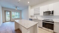Located at 7311 Baymeadows Way in Jacksonville, FL, this well-appointed one-bedroom, one-bathroom residence offers a thoughtfully designed single-story layout with an abundance of functional living spaces. Light-toned wood-style flooring flows throughout, complementing the clean, neutral palette of the interiors.

The open-concept kitchen, dining, and living area serves as the heart of the home. The kitchen is outfitted with crisp white cabinetry, a white subway tile backsplash, granite countertops, a center island for additional prep space, and a full suite of stainless steel appliances including a refrigerator with ice maker, range, dishwasher, and microwave. A ceiling fan overhead and large windows allow natural light to fill the adjoining living area, which opens directly to a private patio overlooking a landscaped courtyard framed by palm trees.

The bedroom is a comfortable, well-sized retreat with a window offering outdoor views and a ceiling fan. Generous storage is provided through four closets, including a walk-in fitted with wire shelving. A versatile den provides additional flexible living space.

The bathroom features a granite-topped vanity with undermount sink, a tiled shower-tub combination, and wood-style flooring. A dedicated laundry area adds everyday convenience to complete this functional and modern residence.