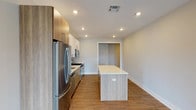 Located at 707 10th Ave in Belmar, NJ, this thoughtfully designed 2-bedroom, 2-bathroom apartment offers a clean, modern aesthetic throughout its well-appointed single-floor layout. The open-concept kitchen serves as the heart of the home, showcasing a large center island with a quartz countertop, two-tone cabinetry combining white upper cabinets with warm wood-finish lower cabinets, and a full suite of stainless steel appliances including a gas range, microwave, dishwasher, and refrigerator. Recessed lighting illuminates the space, which flows seamlessly into a spacious living area featuring warm wood-look flooring and neutral gray walls that lend a bright, airy feel. Both bedrooms are generously sized, each offering double-door closets and the same consistent wood-look flooring and neutral tones. A well-lit hallway connects the main living areas to the bedrooms and bathrooms. The primary bathroom features a dual-sink vanity with wood cabinetry and quartz countertops, a large mirror, and a glass-enclosed walk-in shower with white tile surround. The second bathroom offers a tiled tub-shower combination, a single vanity, and matching modern finishes. Recessed lighting and clean lines carry throughout, giving the entire unit a cohesive, contemporary character.