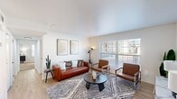 This 790 square foot apartment in Little Rock, Arkansas, offers a harmonious blend of modern design and efficient living. The single-floor layout comprises two bedrooms, one bathroom, a kitchen, living room, and closet space. The primary bedroom, spanning 210 square feet, provides ample space for rest and relaxation.

The open-concept living area is the heart of the home, featuring light wood flooring and large windows that flood the space with natural light. Contemporary furnishings, including sleek armchairs and a stylish coffee table, create a inviting atmosphere atop a geometric patterned area rug. A mid-century modern sideboard adds storage and display space.

The kitchen, while compact, is efficiently designed with white cabinetry, granite countertops, and black appliances. A runner rug adds a touch of comfort to the galley-style layout. The bathroom, glimpsed through hallway views, appears to be updated with modern fixtures.

Both bedrooms feature plush carpeting, ceiling fans, and ample natural light through large windows with blinds. The primary bedroom showcases a leather bench at the foot of the bed and abstract wall art, while built-in closets provide storage solutions.

Throughout the apartment, a cohesive color palette of whites, browns, and blues creates a calming and contemporary ambiance. The property's location at 8101 Cantrell Rd places residents in a desirable Little Rock neighborhood, offering both urban convenience and comfortable living.
