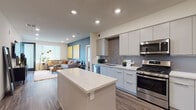 Located at 1465 McCandless Dr in Milpitas, California, this single-story residence showcases a thoughtfully designed open-concept layout with contemporary finishes throughout. The kitchen serves as a central hub of the home, featuring a large quartz-topped island, flat-panel light gray cabinetry extending to the ceiling, a textured gray tile backsplash, and a full suite of stainless steel appliances including a gas range, over-the-range microwave, dishwasher, and French door refrigerator. Recessed lighting illuminates the space, which flows seamlessly into the living area.

The living room is a welcoming, light-filled space accented by a bold teal feature wall, large windows allowing ample natural light, and wood-look plank flooring that runs consistently throughout the home. The bedroom offers a calm, modern retreat with cool gray accent walls, recessed lighting, and bright windows with roller shades.

The bathrooms are equally refined. One features a walk-in glass-enclosed shower and a dual-sink vanity with sleek gray cabinetry and a large mirror. A second bathroom includes a full soaking tub with white subway tile surround and a curved shower rod. The overall ambiance is clean, modern, and cohesive.