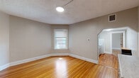 Located at 525 Greenup St in Covington, Kentucky, this one-bedroom, one-bathroom unit offers a well-organized single-floor layout that maximizes every square foot. Warm, honey-toned hardwood floors run throughout the space, lending a classic character complemented by neutral gray walls and crisp white trim and baseboards.

The living room is bright and open, featuring a window that invites natural light and a textured ceiling. It flows naturally into the kitchen area through an arched passageway. The kitchen is efficiently designed with gray shaker-style cabinetry, a white subway tile backsplash, a stainless steel sink, and white appliances including a range and full-size refrigerator, along with a marble-look countertop that adds a clean, modern touch.

The bedroom is a comfortable, well-proportioned retreat with multiple windows offering views of the surrounding greenery, beautiful hardwood floors, a ceiling fan, and a rich, warm-toned wood panel door that adds a charming vintage detail. Three closets throughout the unit provide ample storage.

The bathroom is thoughtfully updated, featuring a walk-in shower clad in large white subway tiles and a classic black-and-white hexagon mosaic tile floor, a pedestal sink with brushed nickel fixtures, a well-lit vanity mirror, and a window for natural light and ventilation.
