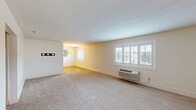 Located at 45 Tamal Vista Blvd in Corte Madera, CA, this one-bedroom, one-bathroom residence offers a thoughtfully organized single-floor layout. The open living room is generously proportioned, featuring neutral carpet flooring, crisp white walls, and large plantation-shuttered windows that allow abundant natural light and views of the surrounding area. A wall-mounted HVAC unit provides individual climate control. The living area flows seamlessly into the combined dining room and kitchen, where warm hardwood-style flooring, white cabinetry with brushed nickel hardware, light stone countertops, and full appliances — including a refrigerator and range — come together in a clean, functional design. A pendant light fixture adds a warm accent to the dining space. The bedroom is a comfortable, well-sized retreat with plush carpet, plantation shutters, a wall-mounted HVAC unit, and a mirrored sliding-door closet that enhances the sense of space. An additional closet provides extra storage. The bathroom features a tiled tub/shower combination with grab bar, a dark-cabinet vanity topped with granite counters, and polished chrome fixtures. A hallway connects the rooms efficiently, completing this well-appointed residence.
