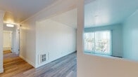 Located at 22828 First St in Hayward, CA, this single-floor unit offers a clean, modern interior with wood-look flooring carried consistently throughout the space. The open layout is anchored by a bright living area featuring crown molding, a wall-mounted heater, and a large sliding glass door that opens to a balcony with open views of the surrounding neighborhood, allowing abundant natural light to fill the room.

The kitchen is efficiently designed with white shaker-style cabinetry, dark countertops, and a full suite of stainless steel appliances including a refrigerator, dishwasher, and range. A pantry cabinet provides additional storage, while a pass-through connects the kitchen to the adjacent living and dining areas.

The bedroom features crown molding, a mirrored sliding closet with wire shelving, and a window with vertical blinds that draw in natural light. A dedicated laundry area with a stacked washer and dryer is conveniently located nearby.

Two bathrooms serve the unit: one full bath with a tiled tub-shower combination, a single vanity, and a large mirror, and a half bath with a vanity and toilet. Throughout, the interior is finished in a neutral white palette, lending the space a bright, clean, and move-in ready character.