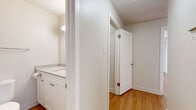 Located at 1000 Brunette Ave in Coquitlam, BC, this well-appointed one-bedroom, one-bathroom unit offers a comfortable and efficiently designed single-floor layout. Warm hardwood-style flooring flows throughout the entire space, lending a cohesive and inviting feel.

The kitchen is a standout feature, boasting an abundance of white shaker-style cabinetry that reaches floor to ceiling, granite-look countertops, a peninsula for additional prep and dining space, and stainless steel appliances including a refrigerator, dishwasher, and range. A textured tile backsplash adds subtle depth to the clean, bright aesthetic.

The living room is generously proportioned and filled with natural light through large sliding glass doors that open onto a private balcony overlooking lush, mature greenery. A baseboard heating system runs along the exterior wall.

The bedroom offers a comfortable footprint with a built-in closet featuring shelving and a hanging rod, accessed via bi-fold doors. Neutral walls and natural light make it a calm, restful retreat.

The bathroom is finished with a wide granite-topped vanity, white cabinetry with brushed nickel hardware, and a large mirror. Textured walls and hardwood-style flooring complete the clean, functional design. A dedicated closet provides additional storage within the unit.