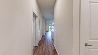 Located at 1235 NASA Pkwy in Houston, TX, this thoughtfully designed 2-bedroom, 2-bathroom residence offers a comfortable and modern living experience across a single floor. The open-concept living and kitchen area is anchored by warm hardwood-style flooring, recessed lighting, and a ceiling fan, creating a bright and inviting atmosphere. The kitchen is a standout feature, boasting rich dark wood cabinetry, granite countertops, a subway tile backsplash with under-cabinet lighting, stainless steel appliances including a gas range, microwave, refrigerator, and dishwasher, plus a central island for additional prep space. Both bedrooms are carpeted and equipped with ceiling fans; the primary bedroom opens to a private balcony with decorative ironwork railing. The primary bathroom impresses with large-format marble-look tile flooring, a dual-sink granite vanity, and a glass-enclosed walk-in shower. The secondary bathroom mirrors the same refined tile work and granite countertop details. A spacious walk-in closet with wire shelving provides ample storage. Clean white walls and neutral tones throughout lend the space a polished, move-in-ready feel.