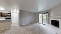 Located in Austin, TX (78759), this 2-bedroom, 2-bathroom residence offers a well-organized single-level layout designed for comfortable everyday living. The spacious living room is a standout, featuring plush carpeting, neutral gray walls, and a white-tiled wood-burning fireplace as a central focal point. A large sliding glass door opens to a private balcony overlooking lush, mature tree canopy, filling the room with natural light and greenery. The kitchen is thoughtfully updated with dark espresso cabinetry, white quartz countertops, a tile backsplash, stainless steel appliances, and wood-style flooring. A peninsula with a built-in sink connects the kitchen to the living area, creating an open, functional flow. The primary bedroom is generously proportioned, featuring carpeted floors, a sliding glass door to its own balcony access with tree views, and a double-door closet. The second bedroom also offers carpet, neutral tones, and a closet. Both bathrooms echo the kitchen's design language with dark cabinetry, white countertops, and wood-style flooring. A dedicated closet provides additional storage. The overall palette of soft grays, whites, and warm wood tones creates a clean, cohesive ambiance throughout.