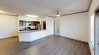 This single-floor, 2-bedroom, 2-bathroom residence combines practical design with modern finishes throughout. The open-concept living and dining area flows seamlessly into the kitchen, which features dark espresso cabinetry, granite-style countertops, stainless steel appliances including a range, built-in microwave, and refrigerator, plus a peninsula with an overhang ideal for casual dining. Wood-look plank flooring runs through the main living areas, adding warmth and durability.

Both bedrooms are carpeted and generously sized, each equipped with a ceiling fan and window with blinds that invite natural light. The primary bedroom connects to a private en-suite bathroom featuring a walk-in shower with glass doors, dark cabinetry, and a granite-topped vanity. A spacious walk-in closet with wire shelving provides ample storage. The second bathroom offers a full tub-shower combination, matching dark cabinetry, and granite countertops.

Crown molding accents the living area, adding a refined touch to the otherwise clean, neutral palette. The layout is efficient and well-organized, with dedicated hallway closets visible from the main living space, enhancing overall storage options throughout the home.