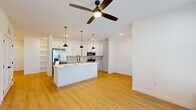 Located at 7750 Norice Grove in Colorado Springs, CO, this well-designed single-story home offers three bedrooms, two bathrooms, and a thoughtful layout that maximizes functionality. Light wood-look flooring flows consistently throughout the home, complementing the clean white walls and creating a bright, cohesive aesthetic.

The open-concept kitchen and living area serves as the heart of the home. The kitchen features a large central island with a sink, white cabinetry, a hexagonal tile backsplash, stainless steel appliances including a refrigerator, microwave, and range, and three stylish pendant lights with black and gold fixtures. The living area is generously sized with a ceiling fan overhead.

The primary bedroom is a comfortable, well-lit retreat featuring a wall of windows that bring in abundant natural light, a ceiling fan, and direct access to a private en-suite bathroom. The en-suite includes a vanity with a lighted mirror, gray tile accent wall, and direct entry into a spacious walk-in closet with dual hanging rods and shelving on both sides. Additional bedrooms are bright and airy, each with windows overlooking the neighborhood and ceiling fans. The home also includes a dedicated laundry area and four closets total for ample storage throughout.