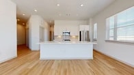 This well-designed single-floor residence offers three bedrooms and three full bathrooms within a thoughtfully laid-out floor plan. The open-concept kitchen and living area serves as the heart of the home, anchored by a large central island with white quartz countertops and an undermount sink. The kitchen features sleek white shaker cabinetry with modern hardware, a subway tile backsplash, and a full suite of stainless steel appliances. Light hardwood flooring flows throughout the main living areas, enhancing the bright, airy aesthetic created by recessed lighting and abundant natural light. The primary bedroom is generously sized, with sliding glass doors opening onto a private balcony that offers open outdoor views, complemented by a ceiling fan and multiple windows. Secondary bedrooms are carpeted and offer comfortable proportions, each with closet access. The bathrooms are finished with marble-style tile surrounds, white vanities with quartz countertops, and a combination of soaking tubs and glass-enclosed showers. A dedicated built-in mudroom/closet area with open shelving and hooks adds practical storage. A laundry room and hallway complete the functional layout, making this a well-appointed and move-in ready space.