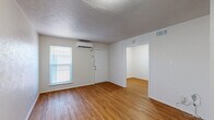 Located at 2269 W Oak St in Denton, TX, this single-floor unit offers an efficient and well-organized layout across its compact footprint. Warm wood-style flooring runs consistently throughout the space, lending a cohesive and inviting feel to every room. The combined kitchen and living area serves as the heart of the unit, where a wall-mounted mini-split HVAC system provides climate control. The kitchen is equipped with gray cabinetry, granite-style countertops, a double basin sink, a gas range, and a full-size refrigerator, offering practical functionality in a tidy arrangement. A dedicated dining area provides a defined space for meals, while a separate room serves as additional living or sleeping space, featuring a window with blinds that allows natural light to filter in. A closet offers dedicated storage, and the bathroom is appointed with a granite-style vanity countertop, an oval undermount sink with chrome fixtures, and a wall mirror. Textured ceilings are present throughout, and the crisp white walls contribute to a clean, neutral aesthetic. The overall layout is straightforward and efficient, making practical use of every area within the space.