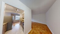 This thoughtfully laid-out one-bedroom, one-bathroom unit spans a single floor, offering a functional and comfortable living environment. The space features classic parquet hardwood flooring throughout the main living areas, lending warmth and a timeless character to each room.

The living room is a bright, open area anchored by a large window with a radiator beneath it, allowing natural light to fill the space while offering views of the surrounding neighborhood. The neutral-toned walls provide a clean, versatile backdrop throughout.

The kitchen is accessed through an arched entryway and is well-equipped with modern gray cabinetry, granite countertops, a double stainless steel sink, a decorative tile backsplash with a mosaic accent border, and stainless steel appliances including a full-size refrigerator. Light tile flooring adds a practical finish to this culinary space.

The bedroom is a cozy, private retreat that continues the parquet flooring and maintains the clean, neutral aesthetic of the rest of the unit. It features its own window and a standard interior door for privacy.

The bathroom is finished with beige ceramic wall tiles surrounding a full bathtub and shower combination, offering a clean and functional design. A connecting hallway ties all rooms together, creating a cohesive and efficient floor plan throughout the unit.