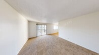 Located at 511 E Sahara Ave in Las Vegas, NV, this 1-bedroom, 1-bathroom unit offers a well-organized single-floor layout comprising a living room, dining room, kitchen, hallway, and two closets. The living area is generously sized, featuring neutral-toned carpet, white walls with a textured ceiling, and a sliding glass door that opens to a private balcony, allowing natural light to flow through the space. A secondary window further brightens the room, offering views of the surrounding area. The kitchen is functional and efficiently designed, featuring white cabinetry, granite-style countertops, hardwood-style flooring, and a full suite of appliances including a refrigerator, electric range, dishwasher, and built-in microwave. The bedroom is a comfortable retreat, highlighted by a distinctive white-painted brick accent wall, plush carpeting, a ceiling fan with light fixture, and a closet with bifold doors. The bathroom features hardwood-style flooring, a white vanity with storage, a wall-mounted mirror with overhead lighting, and accessibility-friendly grab bars. Throughout the unit, a clean, bright, and neutral color palette creates a cohesive and practical living environment.
