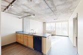 Located at 2347 Arapahoe St in Denver's vibrant Five Points neighborhood, this 2-bedroom, 1-bathroom unit showcases an industrial-modern aesthetic throughout. Exposed concrete ceilings with visible ductwork lend an urban loft character to the space, while hardwood-style flooring runs throughout the main living areas and bedrooms.

The open-concept kitchen features warm maple cabinetry paired with dark countertops, a double-basin sink, black dishwasher, and a black electric range with oven. A peninsula counter provides additional workspace and helps define the kitchen from the living area. Large windows allow generous natural light to fill the connected living space, which benefits from views of the surrounding Denver cityscape.

Both bedrooms carry the same concrete ceiling detail and hardwood-style flooring, with large windows fitted with vertical blinds that invite ample daylight. The primary bedroom offers a comfortable, well-proportioned layout. Baseboard heating units are present in the bedrooms and living area.

The bathroom is efficiently designed with maple cabinetry, a dark countertop vanity, a wide mirror with bar lighting, and a full tub-shower combination. The unit's clean, neutral palette and industrial architectural details make it a functional and characterful home in the heart of Denver.