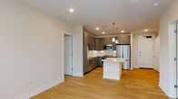 Located at 721 Halifax St in Raleigh, NC, this single-floor residence showcases a clean, contemporary design with consistent light hardwood flooring and neutral warm-toned walls throughout. The open-concept living and kitchen area serves as the centerpiece of the space, offering a seamless flow that makes the layout feel expansive and connected. The kitchen is well-appointed with gray shaker-style cabinetry, a white subway tile backsplash, stainless steel appliances including a refrigerator, range, microwave, and dishwasher, and a large central island topped with striking white quartz countertops featuring subtle veining. Pendant lighting above the island adds a polished finishing touch. The living area is bright and open, with large windows that invite ample natural light and provide views of surrounding greenery. The bedrooms continue the hardwood flooring and neutral palette, with windows offering outdoor views and a calm, airy atmosphere. The bathrooms are finished with large-format neutral tile flooring, gray cabinetry matching the kitchen, white quartz countertops, and backlit mirrors. One bathroom features a full tub and shower with white subway tile surround, while another offers an elongated vanity with generous storage. The overall design is cohesive, modern, and move-in ready.