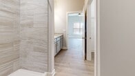 Located at 1151 Knob Hill Blvd in Georgetown, Indiana, this single-story, 3-bedroom, 2-bathroom home offers a clean, modern aesthetic throughout. Light-toned luxury vinyl plank flooring flows seamlessly across the entire floor plan, complementing the neutral gray and white color palette found in every room.

The kitchen is a standout feature, showcasing white shaker-style cabinetry, light granite countertops, and a full suite of stainless steel appliances including a refrigerator with ice maker, electric range, and over-the-range microwave. The open layout connects the kitchen to the living area, creating an inviting and functional shared space.

Each of the three bedrooms offers a comfortable footprint, with large windows dressed in blinds or curtains that allow natural light to fill the rooms. Ceiling fans are present in the bedrooms, adding to everyday comfort. Closets feature wire shelving for organized storage.

The primary bathroom is upgraded with large-format marble-look tile in the walk-in shower and a granite-topped vanity with gray cabinetry. The second bathroom includes a full tub/shower combo with clean white surroundings. The home also includes dedicated utility space housing the water heater, and hallways connecting all areas efficiently. White trim and panel doors complete the fresh, contemporary look throughout.