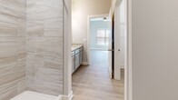 Located at 1151 Knob Hill Blvd in Georgetown, Indiana, this single-story, 3-bedroom, 2-bathroom home offers a clean, modern aesthetic throughout. Light-toned luxury vinyl plank flooring flows seamlessly across the entire floor plan, complementing the neutral gray and white color palette found in every room.

The kitchen is a standout feature, showcasing white shaker-style cabinetry, light granite countertops, and a full suite of stainless steel appliances including a refrigerator with ice maker, electric range, and over-the-range microwave. The open layout connects the kitchen to the living area, creating an inviting and functional shared space.

Each of the three bedrooms offers a comfortable footprint, with large windows dressed in blinds or curtains that allow natural light to fill the rooms. Ceiling fans are present in the bedrooms, adding to everyday comfort. Closets feature wire shelving for organized storage.

The primary bathroom is upgraded with large-format marble-look tile in the walk-in shower and a granite-topped vanity with gray cabinetry. The second bathroom includes a full tub/shower combo with clean white surroundings. The home also includes dedicated utility space housing the water heater, and hallways connecting all areas efficiently. White trim and panel doors complete the fresh, contemporary look throughout.