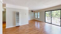 Located at 1225 Walnut St in Napa, CA, this two-bedroom unit offers a practical and comfortable single-floor layout. The open kitchen and living room area is anchored by warm hardwood flooring that runs throughout the common spaces. The galley-style kitchen features white cabinetry, dark countertops, a double-basin sink, and white appliances including an electric range and refrigerator, all illuminated by track lighting overhead. The living room is bright and airy, with a ceiling fan, two windows with blinds, and a sliding glass door that opens to a private balcony overlooking mature trees — bringing natural light and greenery into the space. A wall-mounted HVAC unit provides climate control in the living area. Both bedrooms are carpeted and share a consistent design language, each equipped with ceiling fans and windows that frame views of the surrounding foliage. Each bedroom also features a built-in sliding-door closet with multi-tiered shelving and hanging rods, offering well-organized storage. The neutral color palette and clean finishes throughout lend the unit a calm, functional atmosphere well-suited to everyday living in the heart of Napa.