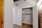 Located at 119 Hotel St in Utica, NY, this thoughtfully designed unit blends industrial character with modern finishes across a well-proportioned single-floor layout. Soaring ceilings with exposed wooden beams and visible ductwork lend an authentic loft aesthetic throughout, while light hardwood flooring ties the living spaces together seamlessly.

The open-concept kitchen is a standout, featuring two-tone gray cabinetry, quartz countertops, a subway tile backsplash, stainless steel appliances, and a peninsula with pendant lighting overhead. Original brick columns and wood beam details add warmth and texture to the space.

Two living areas offer flexibility for living and dining arrangements, each showcasing dramatic exposed brick walls and large black-framed windows that invite natural light and urban views of the surrounding Utica streetscape.

The unit includes two bathrooms finished to a high standard. The primary bathroom features a double navy vanity with quartz countertops, a large backlit mirror, hexagonal tile flooring, and exposed brick accents. The second bathroom mirrors the design language with a single navy vanity, backlit mirror, and a tub-shower combination.

Three closets, including one with built-in shelving and hanging rods, provide generous storage. A hallway and entrance area complete the functional layout of this distinctive, character-rich urban residence.
