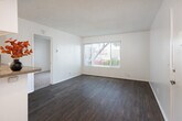 This 450 square foot apartment in Huntington Beach, California, offers a well-designed living space in a single-floor layout. The property features one bedroom, measuring 110 square feet, and one bathroom. The efficient floor plan includes a hallway, closet, and an open-concept kitchen and living room area.

The kitchen is modern and functional, with white cabinetry, a full-sized refrigerator, and a countertop extension that doubles as a breakfast bar. Stainless steel appliances and ample counter space make this compact kitchen both practical and aesthetically pleasing. The living area boasts wood-look flooring and a large window, allowing natural light to flood the space and providing views of the surrounding greenery.

The bedroom features plush carpeting and a window with vertical blinds, offering both comfort and privacy. The bathroom is well-appointed with a vanity, mirror, and a shower/tub combination. Throughout the apartment, the neutral color palette and textured ceilings create a bright, airy ambiance.

This apartment's layout maximizes the use of space, making it an ideal residence for singles or couples looking for a cozy home in the desirable Huntington Beach area.