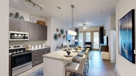 This well-appointed one-bedroom, one-bathroom residence in Cayce, South Carolina offers a thoughtfully designed open-concept layout that maximizes every square foot. The combined kitchen and living area serves as the heart of the home, where a granite-topped island with bar seating anchors the space beneath elegant pendant lighting. Dark, contemporary cabinetry pairs seamlessly with stainless steel appliances, including a range and over-the-range microwave, while a tile backsplash adds a refined finishing touch. Light wood-style flooring flows throughout the main living areas, complementing the bright, neutral color palette.

The living room benefits from large windows and a glass door that invite an abundance of natural light and outdoor views, with a ceiling fan adding comfort. The bedroom is a serene retreat featuring plush carpeting, generous windows with views of the surrounding greenery, and direct access to a walk-in closet. The bathroom is finished with a granite vanity, undermount sink, and contemporary fixtures. A dedicated laundry area and a light-filled hallway with wood-style flooring round out this cohesive and modern living space.