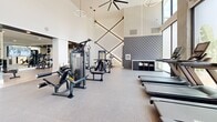 Located at 3314 Piedmont Rd NE in Atlanta's prestigious Buckhead district, this contemporary fitness center delivers a comprehensive workout experience within a generously sized, single-floor facility. The space features soaring double-height ceilings that create an open, airy atmosphere, complemented by expansive floor-to-ceiling windows that flood the interior with natural light and offer views of the surrounding urban landscape.

The main workout floor is divided into distinct training zones. The cardio area is outfitted with a row of treadmills, elliptical machines, and stair climbers, all positioned along the windowed perimeter to maximize natural light. A dedicated strength training zone houses a full suite of cable machines, multi-use weight stations, and resistance equipment on durable rubber flooring. Functional training areas are well-appointed with a heavy punching bag, plyo boxes, battle ropes, and a cable pull station.

A separate studio-style room features light hardwood-style flooring, full-length mirrors, a wall-mounted TV, and a rowing machine, ideal for focused individual training or stretching. Throughout the space, modern ring pendant lighting and large ceiling fans provide both style and comfort. The clean white walls, geometric accent wall treatments, and cohesive modern design aesthetic give the facility a polished, upscale feel suited to its Buckhead location.
