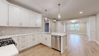 Located at 50 Mount Bethel Rd in Warren, NJ, this single-floor 2-bedroom, 1-bathroom home offers a thoughtfully designed layout with modern finishes throughout. Light wood flooring flows seamlessly across the entire space, creating a warm and cohesive aesthetic.

The open-concept kitchen and living area serves as the heart of the home. The kitchen features crisp white shaker cabinets, light quartz countertops, a subtle stone tile backsplash, and a full suite of stainless steel appliances including a gas range, over-the-range microwave, dishwasher, and French door refrigerator. Pendant lighting over the peninsula and crown molding add refined detail. The adjacent living room is bright and airy, featuring recessed lighting, crown molding, a decorative column accent, and a window that brings in natural light.

Both bedrooms are well-sized and equipped with individual wall-mounted mini-split HVAC units for personalized climate control. The spacious primary bedroom includes ample room for a full furniture arrangement. A dedicated closet offers built-in shelving and hanging rods for organized storage.

The full bathroom is finished with a double-sink vanity in taupe cabinetry, quartz countertops, a large mirror with contemporary lighting, and speckled tile flooring. A hallway connects all rooms, completing this clean and move-in-ready home.