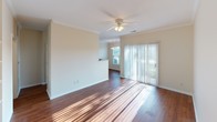 This single-floor, 2-bedroom, 2-bathroom residence offers a practical and well-organized layout suited for everyday living. The living area features rich hardwood flooring, crown molding, and a ceiling fan with light fixture, while a sliding glass door floods the space with natural light and provides access to an outdoor patio. Built-in shelving adds a distinctive architectural detail, offering both display and storage options.

The galley-style kitchen is equipped with warm wood cabinetry, dark stone-look countertops, and black appliances including a refrigerator, electric range with microwave above, and dishwasher. Hardwood flooring continues throughout, connecting seamlessly to the main living areas.

Both bedrooms are carpeted and receive natural light through windows fitted with blinds. The primary bedroom includes a private en-suite bathroom featuring a walk-in shower with sliding glass doors, wood-tone vanity cabinetry, and hardwood flooring. The second bathroom offers a tub-shower combination with tile surround.

A dedicated in-unit laundry area houses a full-sized washer and dryer set with an overhead wire shelving rack, adding notable convenience to the residence.