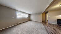 Located at 2704 Westmar Ct in Toledo, Ohio, this one-bedroom, one-bathroom unit offers a practical and well-organized single-floor layout. The combined kitchen and living area forms the heart of the space, with the kitchen featuring gray cabinetry, a double-basin sink, laminate countertops, and black appliances including a range and full-size refrigerator. Durable wood-look vinyl plank flooring runs throughout the kitchen area, transitioning into plush carpeting in the living and bedroom spaces. The living room receives natural light through a large window fitted with vertical blinds, and is equipped with a wall-mounted air conditioning unit and baseboard heating. Neutral taupe-toned walls and a textured ceiling carry throughout, creating a cohesive and understated aesthetic. The bedroom is a comfortable size, offering a full-panel closet with louvered doors for ample storage, a window for natural light, and continued baseboard heating. Three closets total provide generous storage across the unit. The bathroom is clean and functional, featuring a tub/shower combo, a single-sink vanity with white cabinetry, and wood-look vinyl flooring. Baseboard heating is present here as well, ensuring consistent warmth throughout the entire unit.